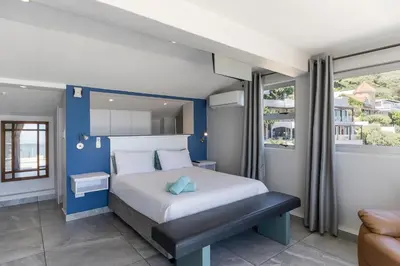 a bedroom with a large bed with a blue wall at 34 Gordonia, Beachfront Penthouse in Gordonʼs Bay