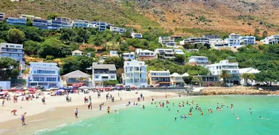 a group of people on a beach in the water at 34 Gordonia, Beachfront Penthouse in Gordonʼs Bay