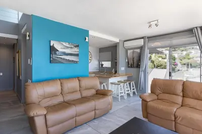 a living room with two leather couches and a blue wall at 34 Gordonia, Beachfront Penthouse in Gordonʼs Bay