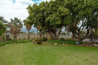 a yard with grass and trees and a fence at The Ocean Side Cottage in Cape Town