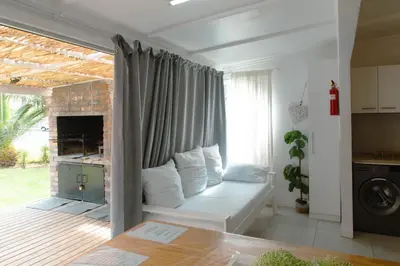a living room with a couch in front of a window at The Ocean Side Cottage in Cape Town