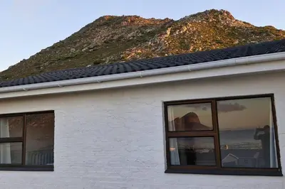 a building with windows and a mountain in the background at Paradise 'tween sea and mountain in Pringle Bay