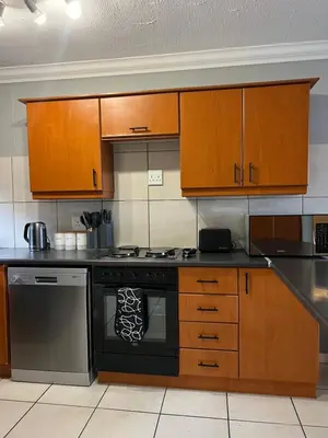 a kitchen with a stove and wooden cabinets at Tyger waterfront apartment in Cape Town
