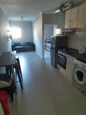 a kitchen and living room with a stove and a washing machine at Astros Lodge in Cape Town