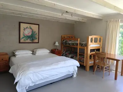 a bedroom with a bed and a desk and a table at Scenic Bliss Holiday Home in Kleinmond