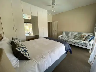 a bedroom with a large white bed and a couch at Onrus Beach House in Hermanus