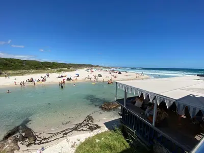 a beach with a bunch of people in the water at Onrus Beach House in Hermanus