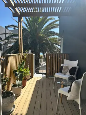 a wooden deck with chairs and a palm tree at Sunset Studios in Cape Town