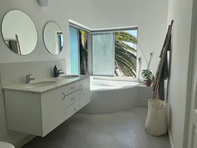 a bathroom with two sinks and a bath tub with a window at Sunset Studios in Cape Town