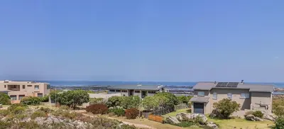 a row of houses with the ocean in the background at Penguin's Nest in Bettyʼs Bay