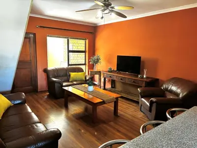 a living room with leather furniture and a flat screen tv at Gordon's Bay Townhouse in Gordonʼs Bay
