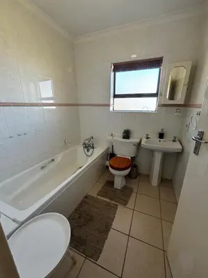 a bathroom with a tub and a toilet and a sink at Gordon's Bay Townhouse in Gordonʼs Bay