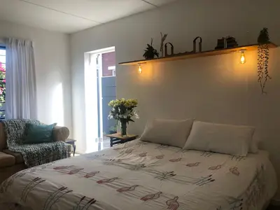 a bedroom with a bed and a chair at Serene Studio in Cape Town