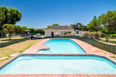 a swimming pool in a yard with a house at Serene Studio in Cape Town