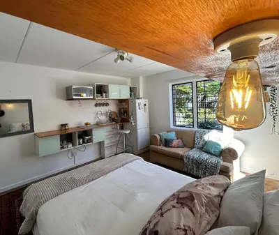 a bedroom with a bed and a couch in a room at Serene Studio in Cape Town