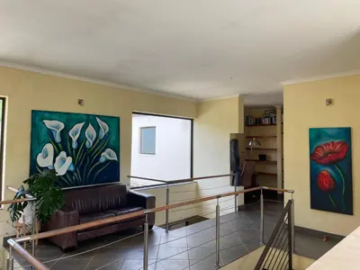 a living room with a couch and two paintings on the wall at Basco River Lodge Holiday Villa in Grabouw