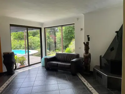 a living room with a couch and a tv and a pool at Basco River Lodge Holiday Villa in Grabouw