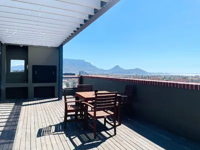 a patio with a table and chairs on a roof at Studio in the City in Cape Town