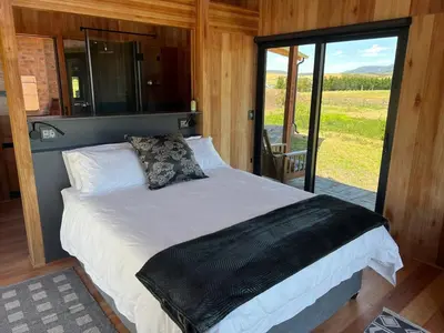 a bedroom with a bed in a room with a window at Natimby Lodge in Botrivier