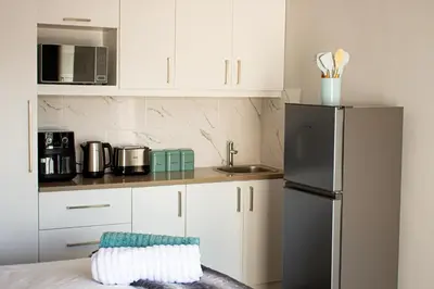 a kitchen with white cabinets and a refrigerator at Annebella's in Gordonʼs Bay