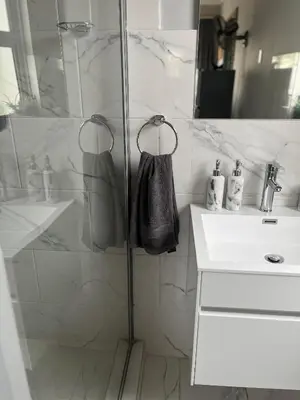 a bathroom with a shower and a sink and a mirror at Annebella's in Gordonʼs Bay