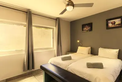 a bedroom with two beds and a window at Bikini Beach Townhouse in Gordonʼs Bay