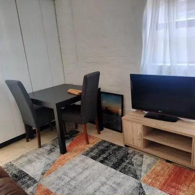 a living room with a table and a television at The Berna in Cape Town