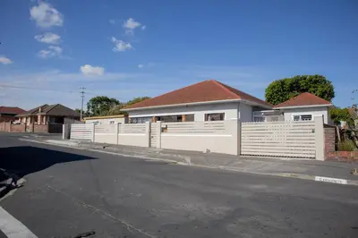 a white fence in front of a house at one bedroom apartment A1 in Cape Town