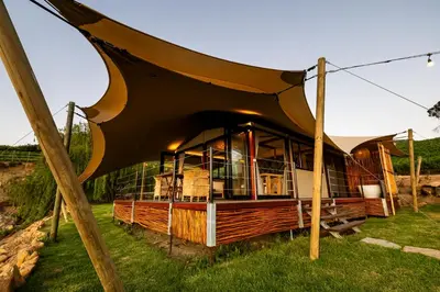 a building with a curved roof in the grass at Amperbo Glamping in Cape Town