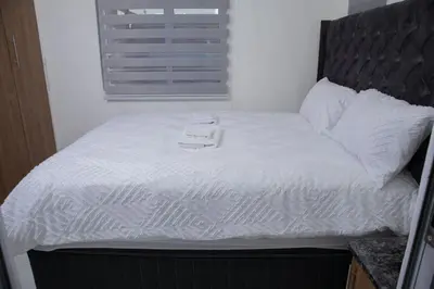 a bed with white sheets and a black headboard at One Bedroom apartment A3 in Cape Town