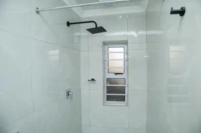a white bathroom with a shower with a window at One Bedroom Apartment A4 in Cape Town
