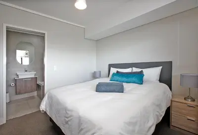 a bedroom with a large white bed with a blue pillow at Waters Edge Uno in Cape Town