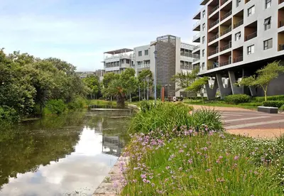 a river in a city with buildings and flowers at Waters Edge Uno in Cape Town