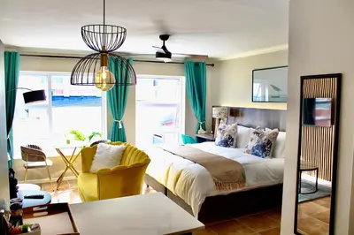 a bedroom with a bed and a desk and a chair at Yellow Couch Studio Apartment 1 KingBed in Cape Town