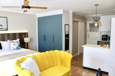 a bedroom with a bed and a yellow chair at Yellow Couch Studio Apartment 1 KingBed in Cape Town