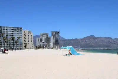 a person standing on a beach with a blue tent at Yellow Couch Studio Apartment 1 KingBed in Cape Town