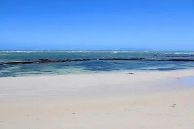 a sandy beach with the ocean in the background at Yellow Couch Studio Apartment 1 KingBed in Cape Town