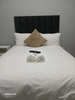 a white bed with two slippers on top of it at The Gem Guest House & Spa in Parow
