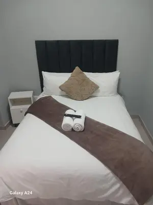 a bed with two rolled towels on top of it at The Gem Guest House & Spa in Parow