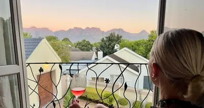 a woman holding a glass of wine looking out a window at Vendôme in Somerset West