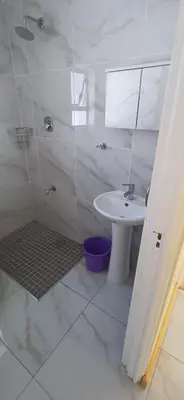 a white bathroom with a sink and a shower at Cosy Cove in Grassy Park
