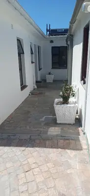 a courtyard of a white building with a potted plant at Cosy Cove in Grassy Park
