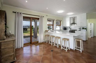 a kitchen with a large white counter and bar stools at Fisherhaven in Hermanus