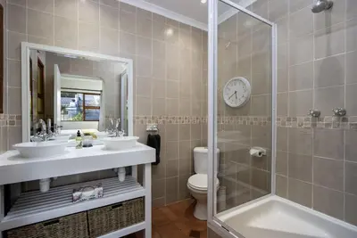 a bathroom with two sinks and a shower and a toilet at Fisherhaven in Hermanus
