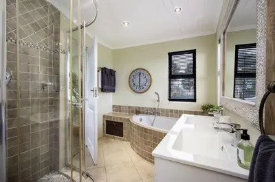 a bathroom with a tub and a clock on the wall at Fisherhaven in Hermanus
