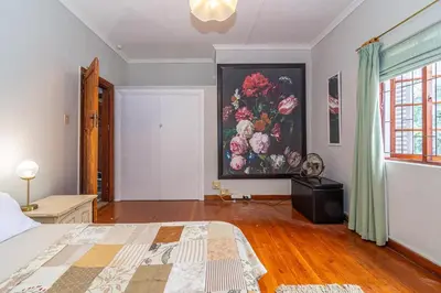 a bedroom with a painting of flowers on the wall at 162 on 6th in Hermanus