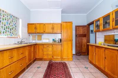 a large kitchen with wooden cabinets and a red rug at 162 on 6th in Hermanus