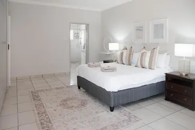 a white bedroom with a large bed with pillows at Seabreeze at the Beach in Strand