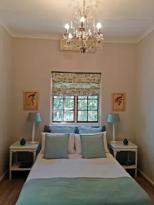 a bedroom with a bed with a chandelier and two tables at Diemersfontein Wine & Country Estate in Wellington