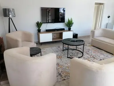 a living room with chairs and a table and a tv at Urban Sleek Black Haven in Cape Town